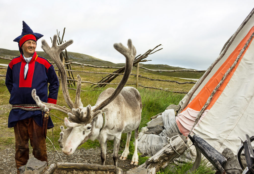 Deer and reindeer breeder dressed in national clothes the Sami in the area of town Honningsvag, Norway.