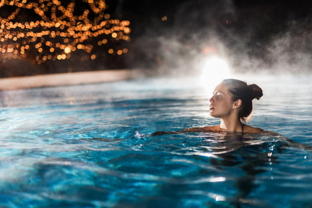 Young woman enjoying in a heated swimming pool at night.